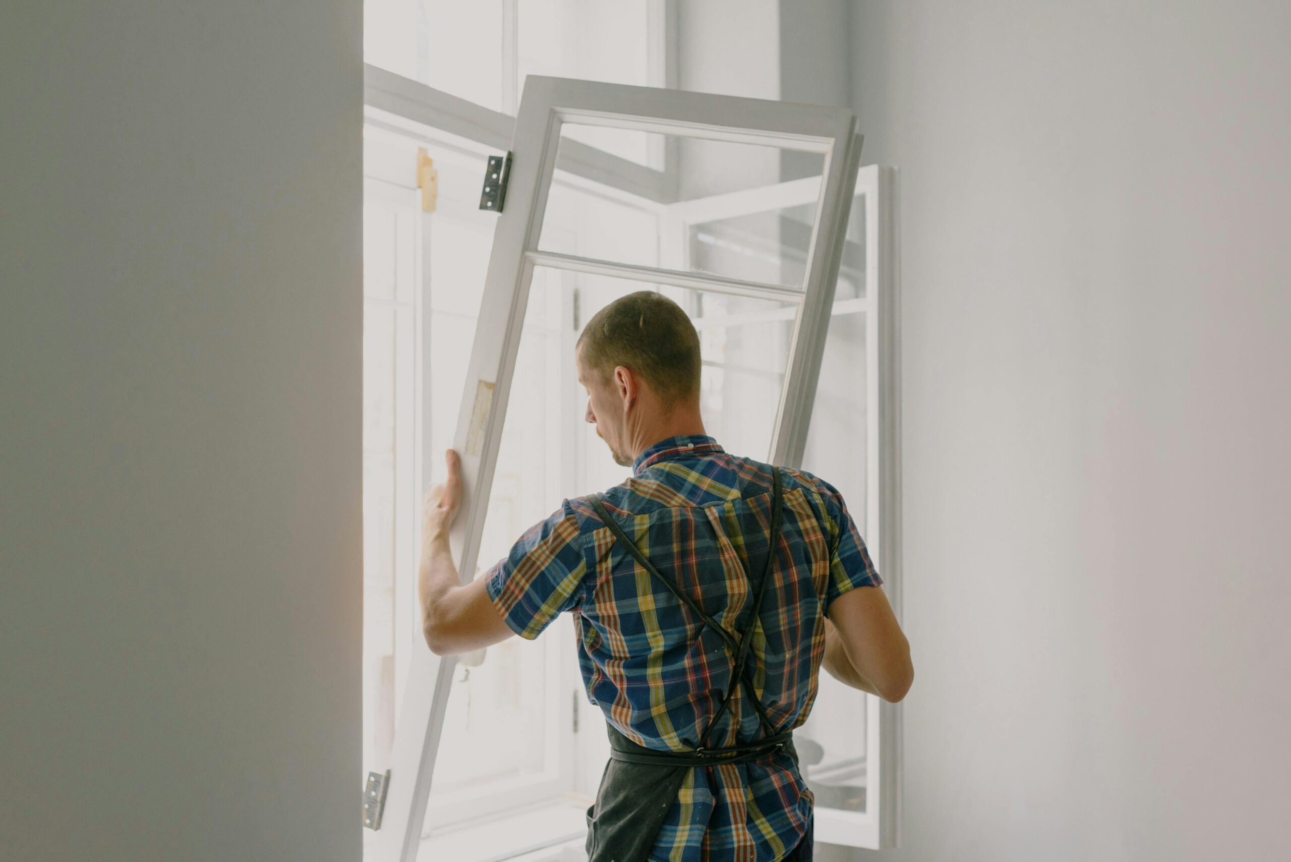 A professional installer fitting a modern window in a well-lit home interior.